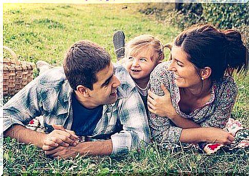 Two parents playing with young daughter in the grass