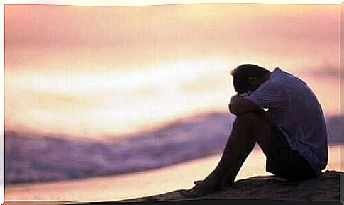 A sad man sitting by the beach thinking about external emotion regulation.