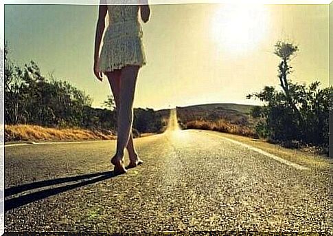 A woman walking barefoot in the middle of the country road.