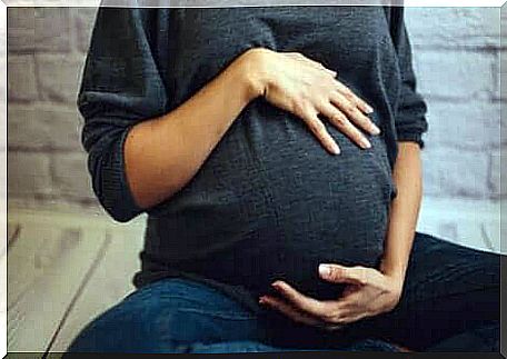 A pregnant woman holding on to her belly.