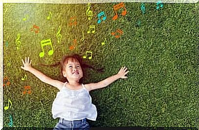 Happy girl lying on the grass listening to music