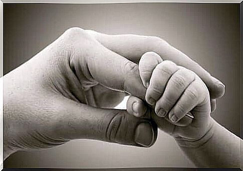 Baby holds mother's hand