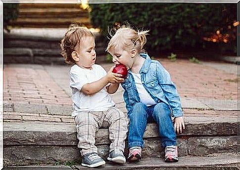 Two children sharing an apple.