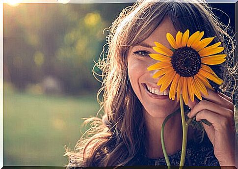 Woman holding a sunflower and showing self-love